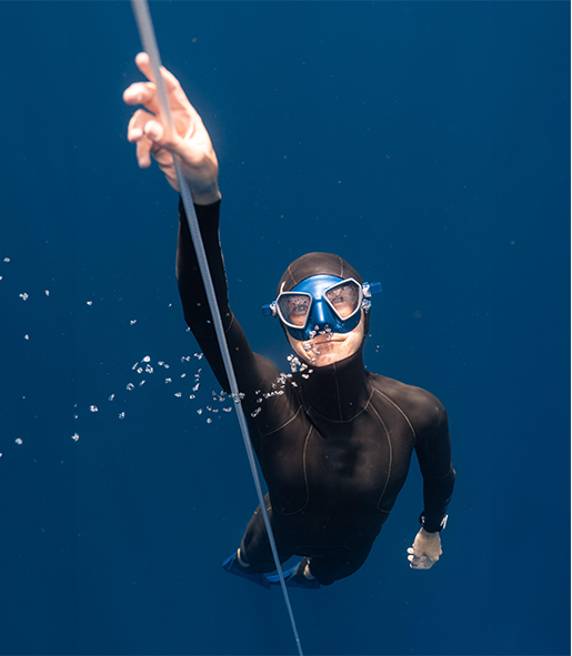 foto di Alessia Zecchini sott'acqua con maschera e muta da sub che si tiene ad un cavo che va verso l'alto